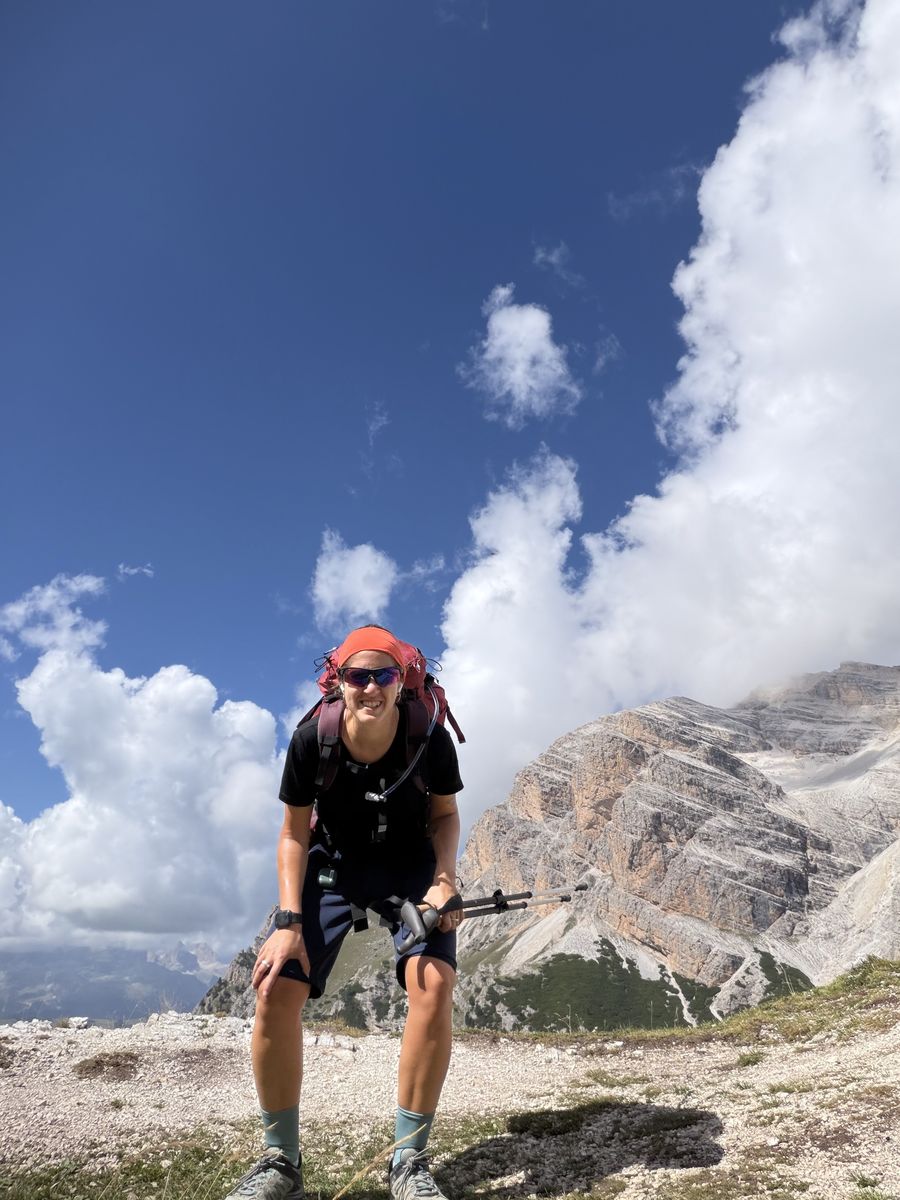 Gemma sul sentiero con zaino e bastoncini, davanti alle Dolomiti